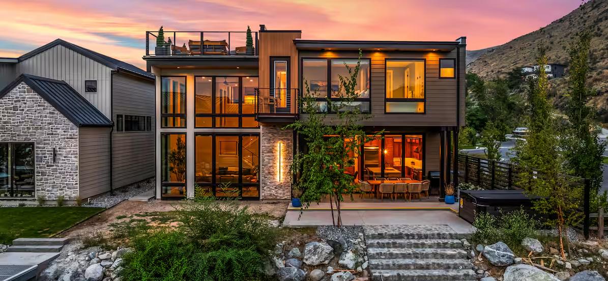 Rear elevation of a modern luxury short-term rental at dusk with mountain backdrop