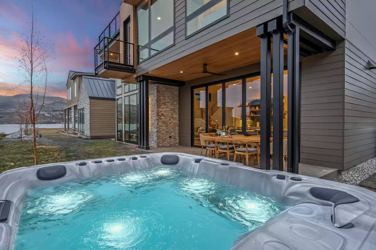 Outdoor spa and covered dining area of a luxury short-term rental at dusk